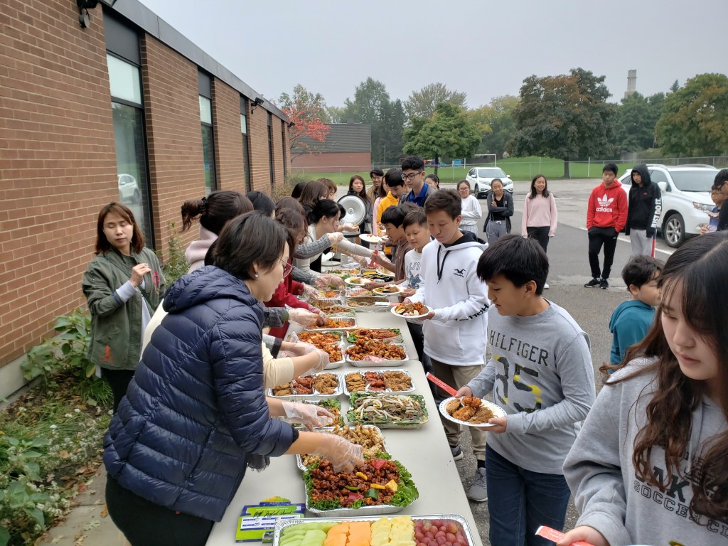 Children getting food from a buffet. Parents volunteering with handing out food. 