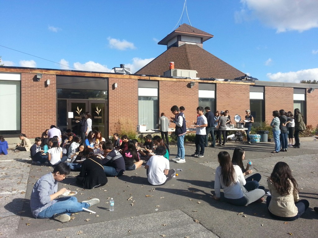 Group of youth sitting in the parking lot of a church. 