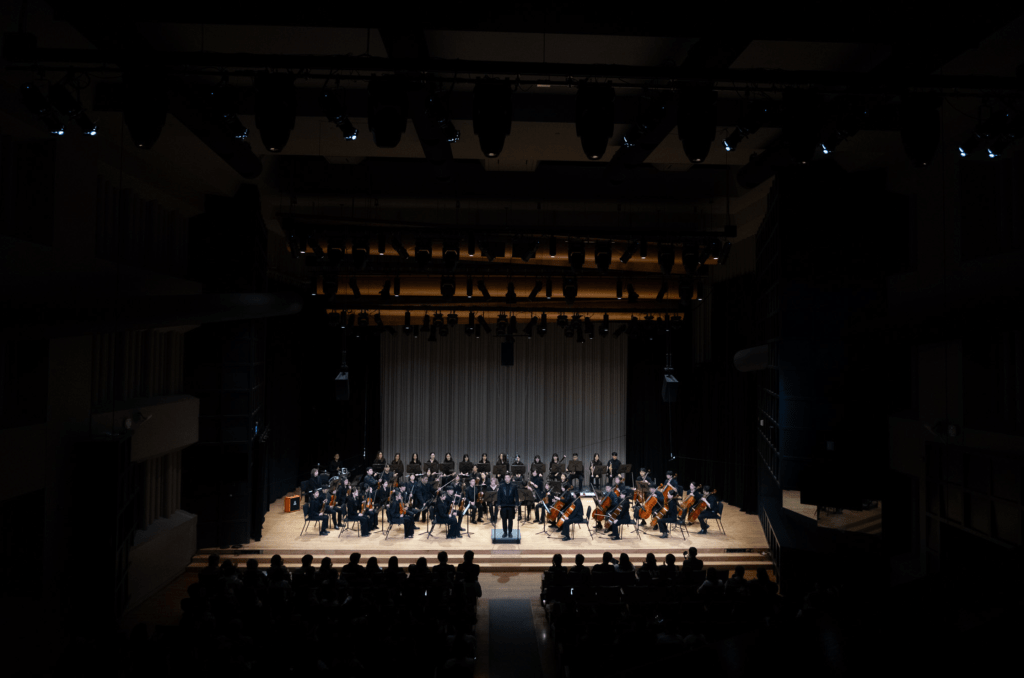 Music students on stage after a live concert holding classical instruments.