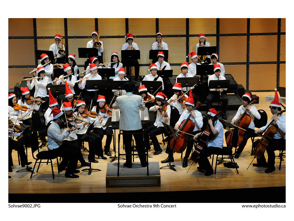 Musicians wearing Santa hats and performing on stage. 